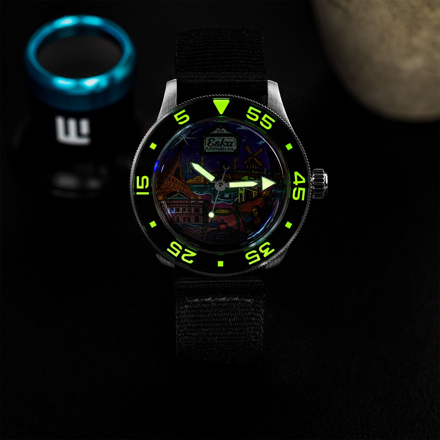 ESKA Amphibian Cœur de Paris — Lume shot in the dark, the dial markers glowing above the hand-painted Parisian cityscape on a 40mm steel diver, customized limited edition by IFL Watches.