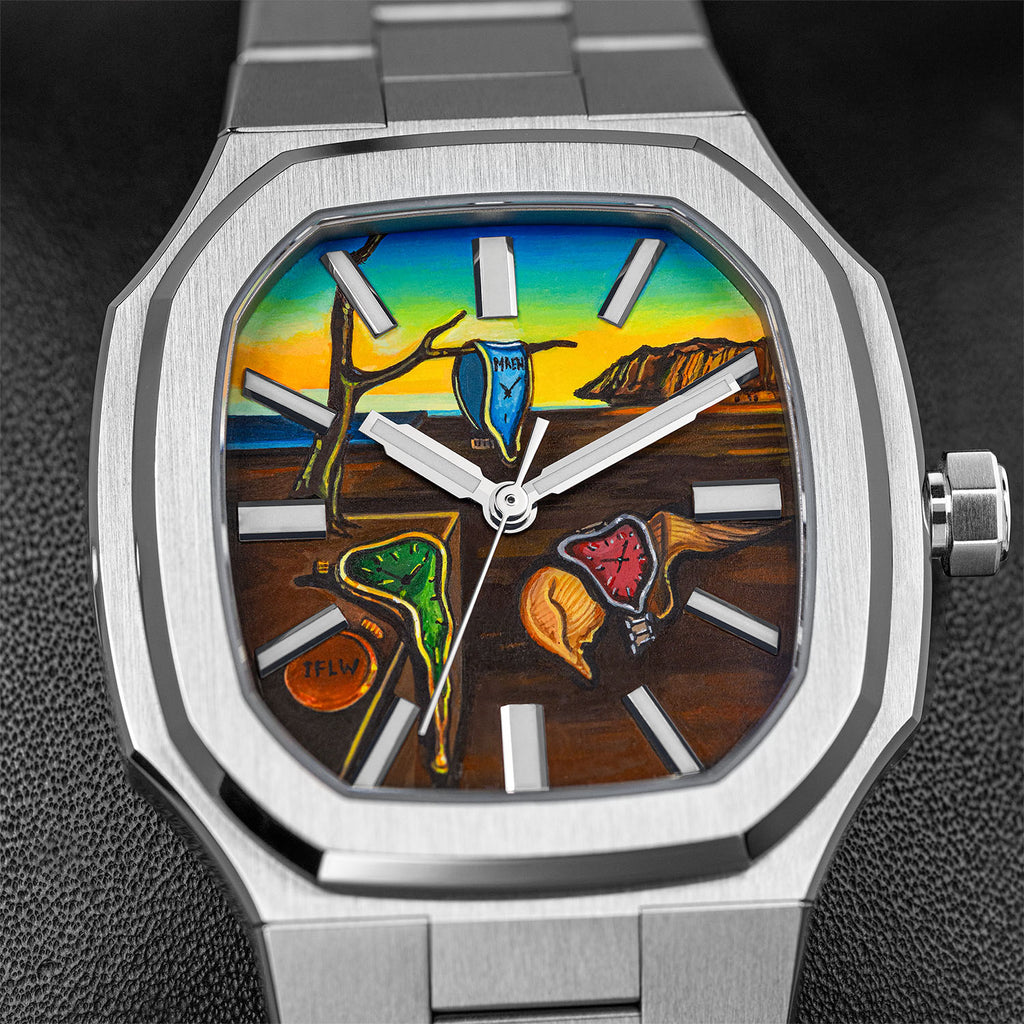 MAEN Manhattan Memento — Close-up of the hand-painted custom dial, a blue soft watch marked MAEN on a bare branch, a green soft watch over a stone plinth beside a closed orange watch marked IFLW and a red soft watch on a golden form, between silver baton markers, a bespoke timepiece by IFL Watches.