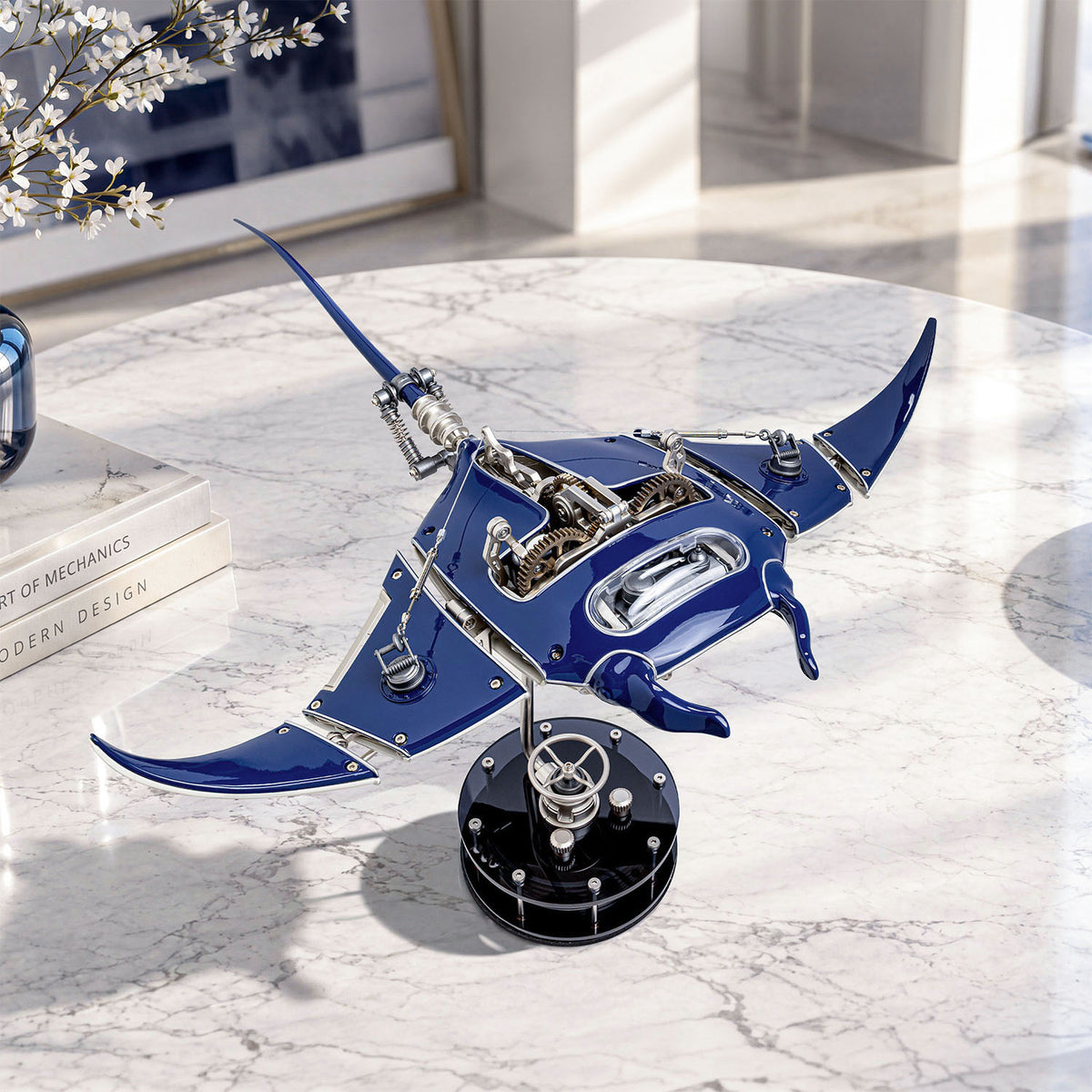 Mecha Ray Blue — displayed on a marble table beside design books and a flowering branch, kinetic sculpture by IFL Watches.