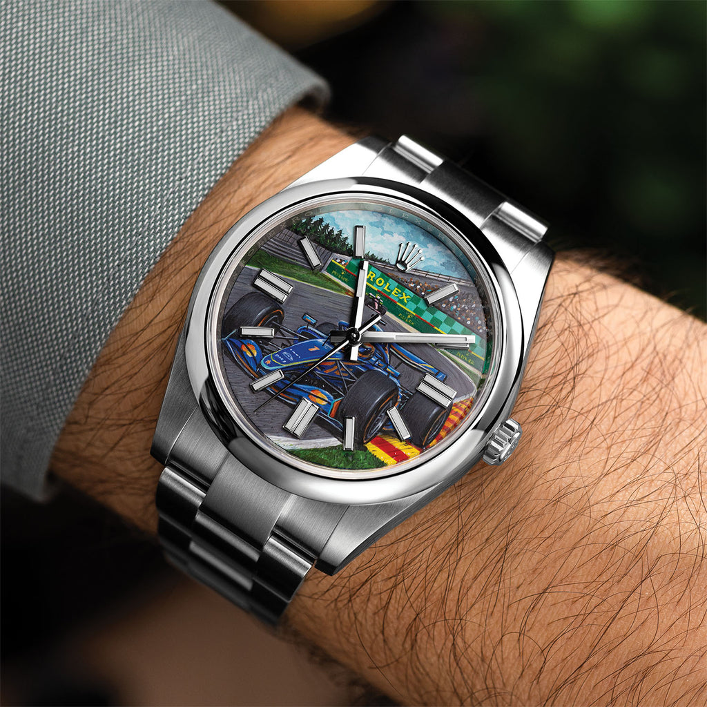 Apex Concept — Custom hand-painted dial worn on the wrist, showing the blue race car mid-corner against green verge and grandstand, a bespoke timepiece by IFL Watches.