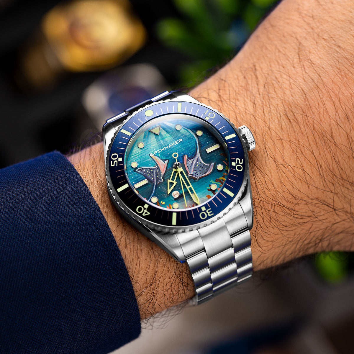 Spinnaker Spence Underwater Dancers — Worn at an angle, steel bracelet and blue bezel against a navy sleeve, limited edition timepiece by IFL Watches.