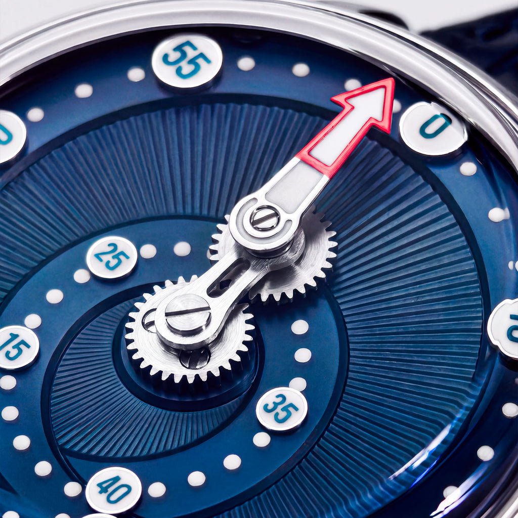 Mandetbrote Orbital Blue Kiss — Macro detail of the geared minute arm and red-tipped hand over the radiating dial texture, available at IFL Watches.